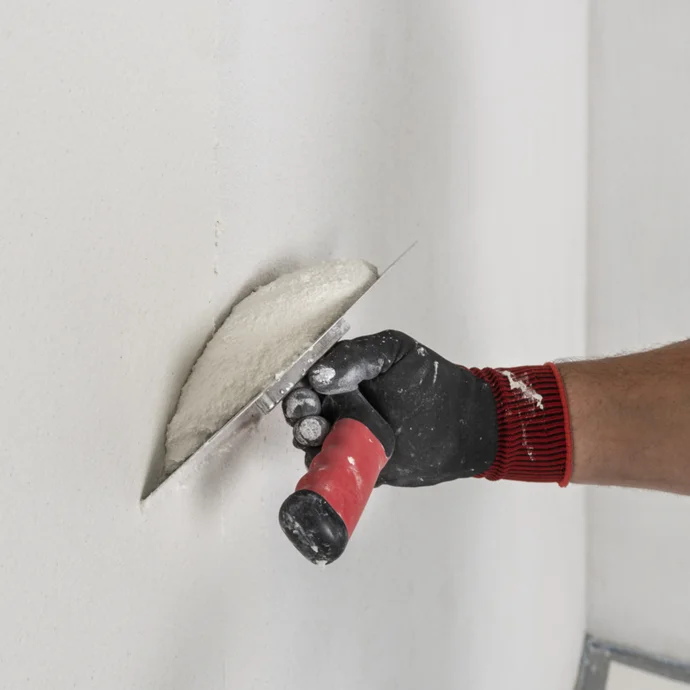 wei&szlig;en, angemischten Filzputz mit Gl&auml;ttkelle auf die Wand auftragen