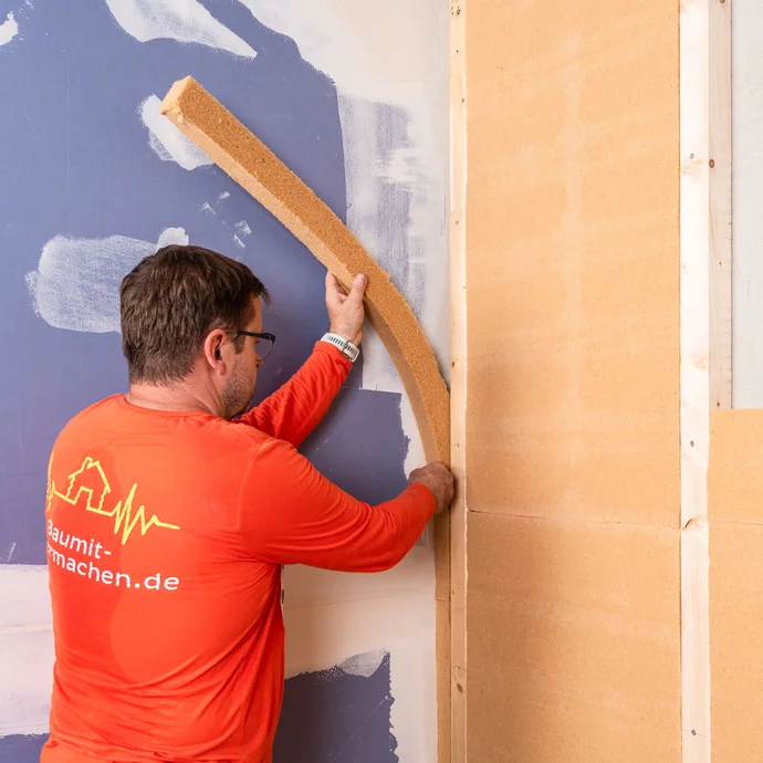 Der Handwerker dämmt die Innenecke von zwei Außenwänden. So werden Wärmebrücken bei der Innendämmung vermieden.