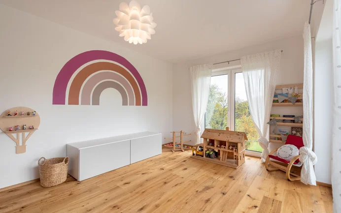 Moderne kinderkamer met speelgoed, een houten vloer en de stralend witte afwerkpleister InStyle Edelwit met een gevilte pleisterstructuur voor een aangenaam binnenklimaat.
