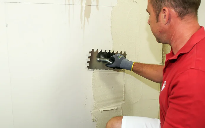Een vakman brengt de pleister AS 2 in 1 aan op de muur.