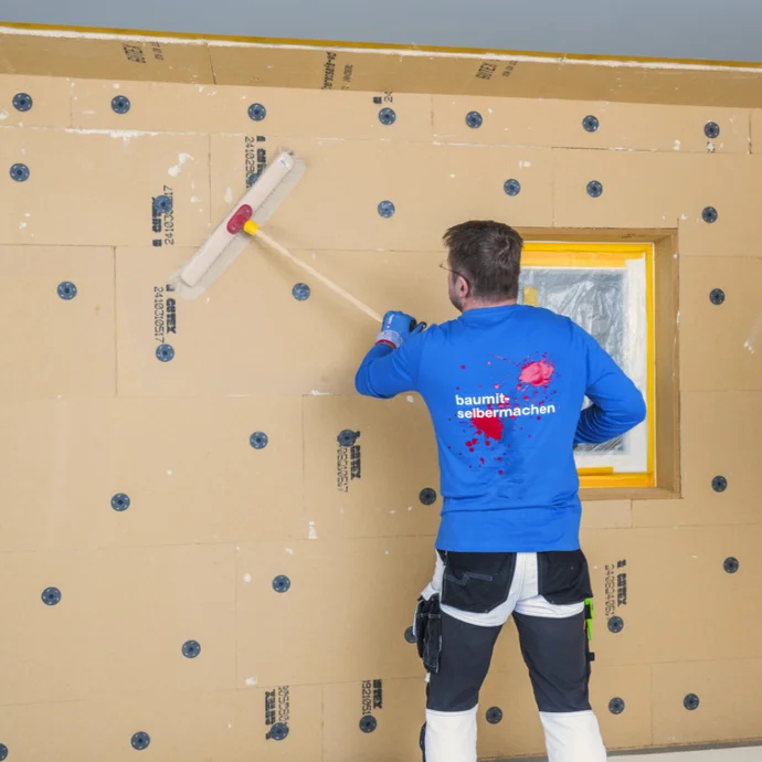 Heimwerker montiert Fassadend&auml;mmung mit Baumit-Produkten, Fensterbereich wird pr&auml;zise bearbeitet.