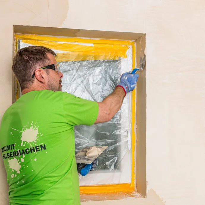 Heimwerker tr&auml;gt Baumit Kalkin Kalkspachtel mit einer Gl&auml;ttkelle in der Fensterlaibung auf &ndash; Kalkspachtel auch in Laibungen sauber und gleichm&auml;&szlig;ig verarbeiten, Baumit Selbermachen Anleitung.