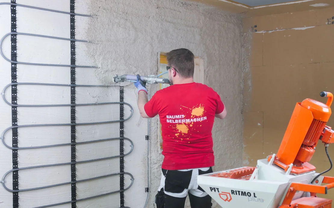 Handwerker verputzt die Wand mit einer Wandheizung professionell mit der Maschine PFT RITMO L.