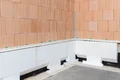 De Baumit plintisolatieplaten worden in de eerste stap langs het huis gelijmd.