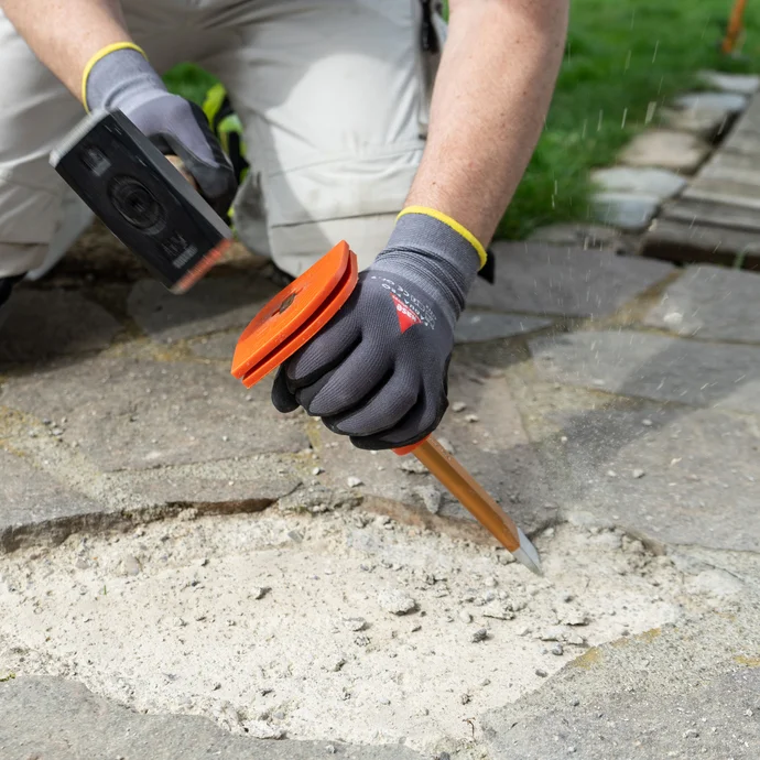 Mit Hammer und Meißel wird der Untergrund für das spätere Verkleben der Natursteinplatte vorbereitet.