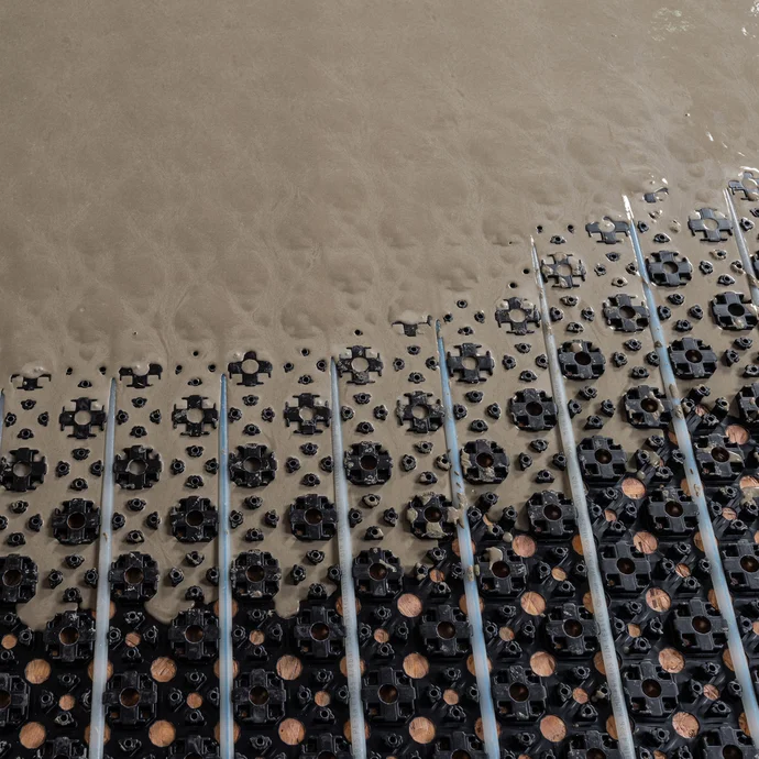 Detailfoto: Noppenplatte mit Heizschläuchen - die selbst nivellierende Ausgleichsmasse füllt die Noppenplatte vollständig.