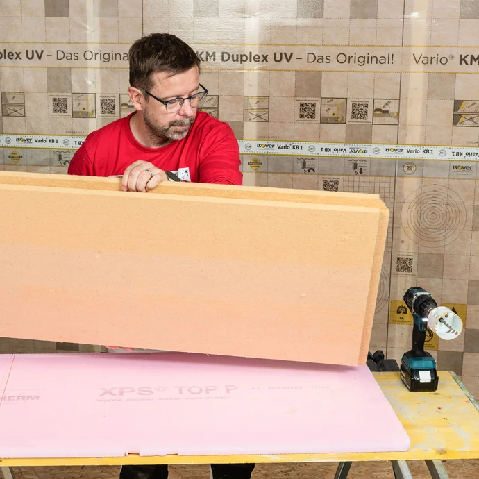 Der Heimwerker dreht die Holzfaserdämmplatte mit Nut und Feder um, sodass er ein Loch durch die Platte ohne Ausbrüche sauber aussägen kann. Tipp aus der Praxis für Heimwerker. Baumit Anleitung zum Selbermachen.